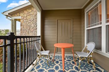a small table and two chairs sit on a balcony in front of a door